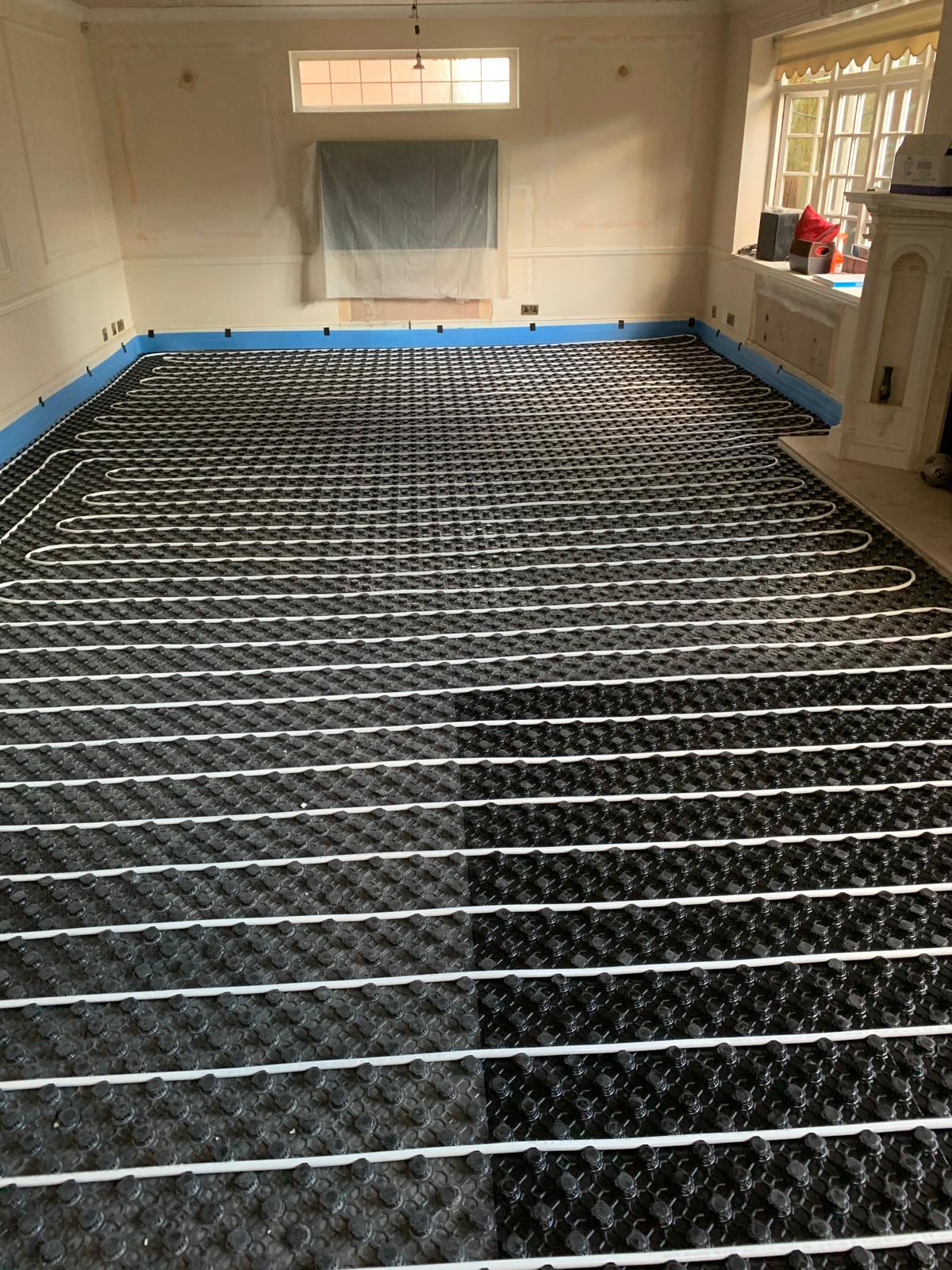 Wet underfloor heating pipework laid across tacker insulation panels in a large room